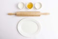 Egg, flour, milk, wooden rolling pin and white plate on white background Royalty Free Stock Photo