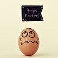 egg with a funny face with a signboard with the text happy easter Royalty Free Stock Photo