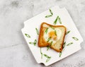Egg in a hole toast with black pepper and green onions on a white rectangular plate on a light gray background Royalty Free Stock Photo