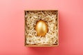 Egg made of gold in a wooden box on a pink background. The concept of exclusivity and superprize. Minimalistic composition