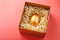 Egg made of gold in a wooden box on a pink background. The concept of exclusivity and superprize. Minimalistic composition