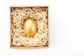 Egg made of gold in a wooden box on a white background. The concept of exclusivity and superprize. Minimalistic composition Royalty Free Stock Photo