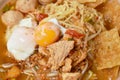 Egg noodles topping pork ball and meat with soft boiled yolk in spicy tom yum soup in bowl on table Royalty Free Stock Photo