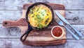 Egg omelette in cast iron skillet on wooden chopping board and r