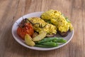 Egg omelette on a piece of black bread with red tomatoes, green beans and fried potato on a wooden table, close up. Breakfast conc Royalty Free Stock Photo