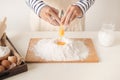 Egg poured into flour during the baking process, man`s hands