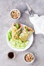 Egg rolls filled with pastrami, vegetables and green onions on a plate, sprouted grains and soy sauce in bowls on the table. Royalty Free Stock Photo