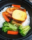 Egg salmon and vegetables hot meal in the black bowl serve for urgently time Thailand