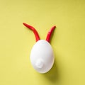 Egg shell and red hot chilli pepper imitation rabbit hare face of devil clown on yellow colored background pape Royalty Free Stock Photo