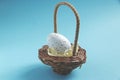 Egg in a small decorative basket on a blue background Royalty Free Stock Photo