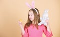 Egg is a symbol of a new life. Cute child with Easter bunny rabbit bringing egg. Little girl holding Easter egg and