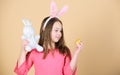 Egg is a symbol of a new life. Cute child with Easter bunny rabbit bringing egg. Little girl holding Easter egg and