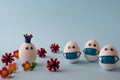 Egg wearing corona, eggs wearing medical mask for stop coronavirus and models of covid-19 virus on blue background. Epidemic