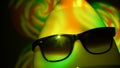 Egghead man in sunglasses in the multicolored spotlight