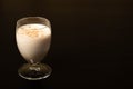 Eggnog Christmas cocktail on a black background. One wine glass. . Royalty Free Stock Photo