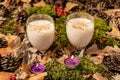 Eggnog Christmas cocktail and two tea candles on the forest substrate. Royalty Free Stock Photo