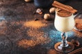 Eggnog cocktail hot winter or autumn drink with milk, eggs and dark rum, sprinkled with cinnamon and nutmeg in shot glass on blue Royalty Free Stock Photo