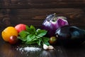 Eggplant (aubergine) with basil, garlic and tomatoes on dark wooden table. Fresh raw farm vegetables - harvest from the Royalty Free Stock Photo
