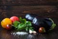 Eggplant (aubergine) with basil, garlic and tomatoes on dark wooden table. Fresh raw farm vegetables - harvest from the Royalty Free Stock Photo