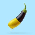 Eggplant with dripping yellow paint on blue background. Creative minimal food concept