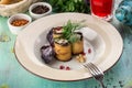 Eggplant rolls stuffed with cottage cheese and walnuts and glass of red drink on blue wooden table