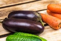 Eggplants, carrots and cucumbers on a wooden background Royalty Free Stock Photo