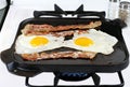 Eggs and Bacon Frying on Griddle