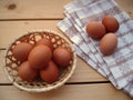 Eggs in the basket and on the kitchen towel on a wooden table, rustic styl