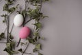 Eggs with beautiful eggshell, pink and white colors with dried maple twigs, leaves flat lay on pastel neutral cream grey.