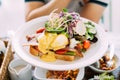 Eggs Benedict served with toast, crispy bacon, asparagus, sliced tomato and rocket salad mix with sliced purple cabbage, green oak Royalty Free Stock Photo