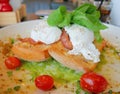 Eggs Benedict on toast with bacon, rocket salad, avocado sauce and tomatoes