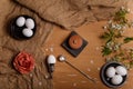 Eggs in black bowls and egg cup with silver spoon, salt pot, fabric rose flower and cherry blossom and petals on sackcloth Royalty Free Stock Photo