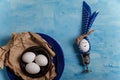 Eggs on brown paper and blue plate. Easter bunny made from egg, polka dot napkin ears in silver egg cup on wooden blue background Royalty Free Stock Photo