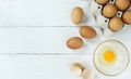 Eggs in a clear cup around with a shell and an egg in a paper plate on a white wooden table in top view. Royalty Free Stock Photo