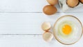 Eggs in a clear cup around with a shell and an egg in a paper plate on a white wooden table in top view. Royalty Free Stock Photo