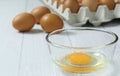 Eggs in a clear cup around with a shell and an egg in a paper plate on a white wooden table in top view Royalty Free Stock Photo
