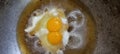 eggs with double yolks being cooked in hot palm oil in an old metal skillet