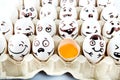 Eggs with drawn cartoon faces and one broken egg in tray.