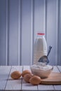 Eggs flour in bowl scoop bottle of milk on white