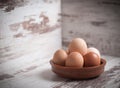 Eggs inside a clay plate over wooden background with copy space