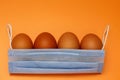 eggs and medical mask on a yellow background, metaphor with a basket. The concept of Easter in isolation Royalty Free Stock Photo