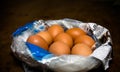 Eggs on newspaper in plastic bag on dark brown wooden table