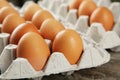 Eggs in the package on brown wwoden background. Royalty Free Stock Photo
