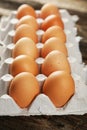 Eggs in the package on brown wwoden background. Royalty Free Stock Photo