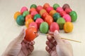 Eggs are painted by hands of person against paintbrush on marble top preparing for easter day.