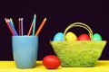 Eggs and pencils Coloured crayons in blue mug and Easter decorations in green basket Royalty Free Stock Photo