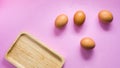 Eggs on a pink bckground with wooden tray