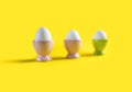 3 eggs in stands on a yellow background.