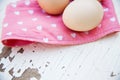 Eggs on tablecloth over wooden background