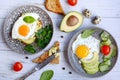 Eggs, toast, avocado, tomatoes and herbs on plates on a wooden background. View from above. Healthy and tasty breakfast Royalty Free Stock Photo